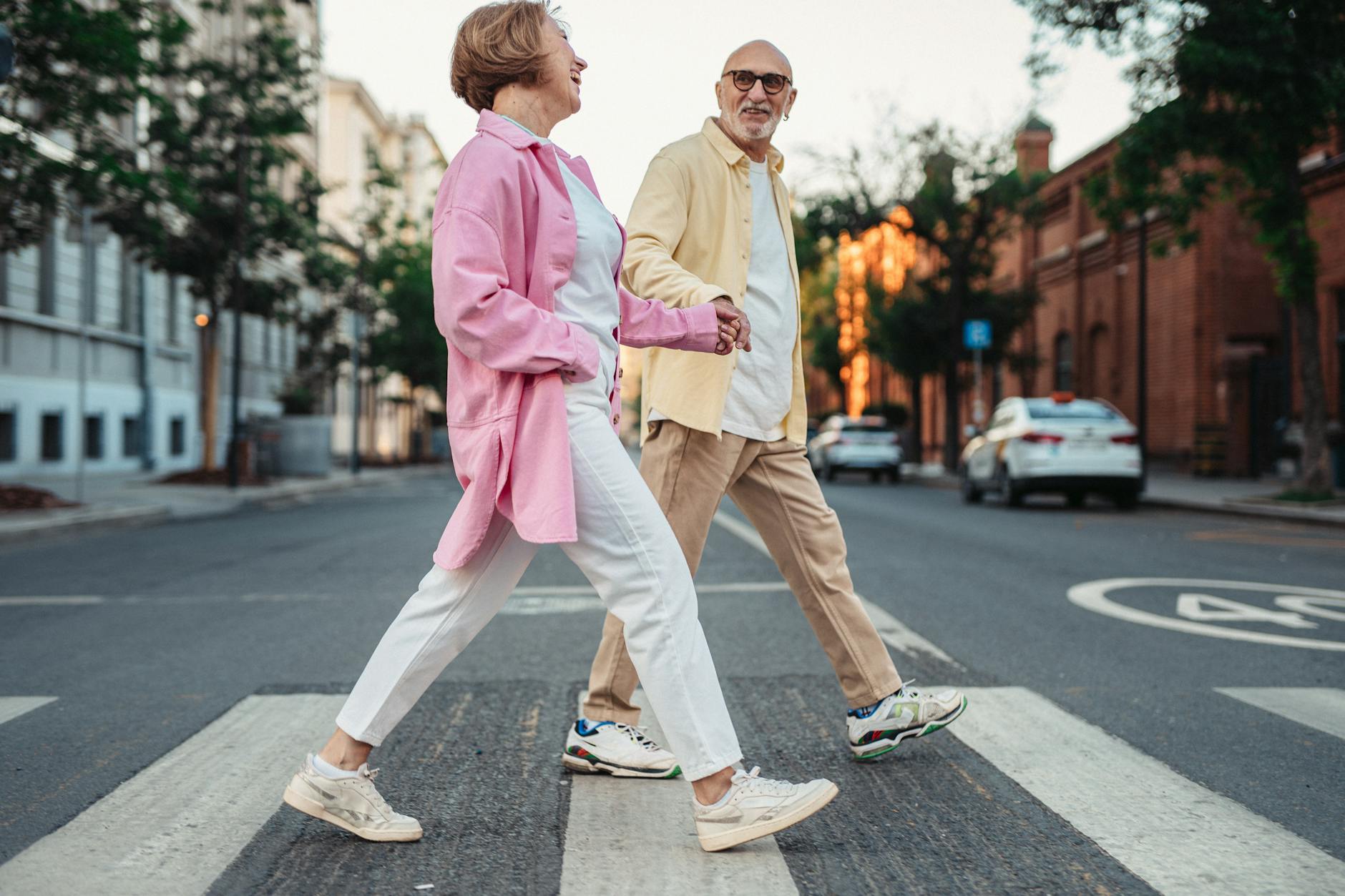 happy elderly couple holding hands while crossing on the pedestrian lane